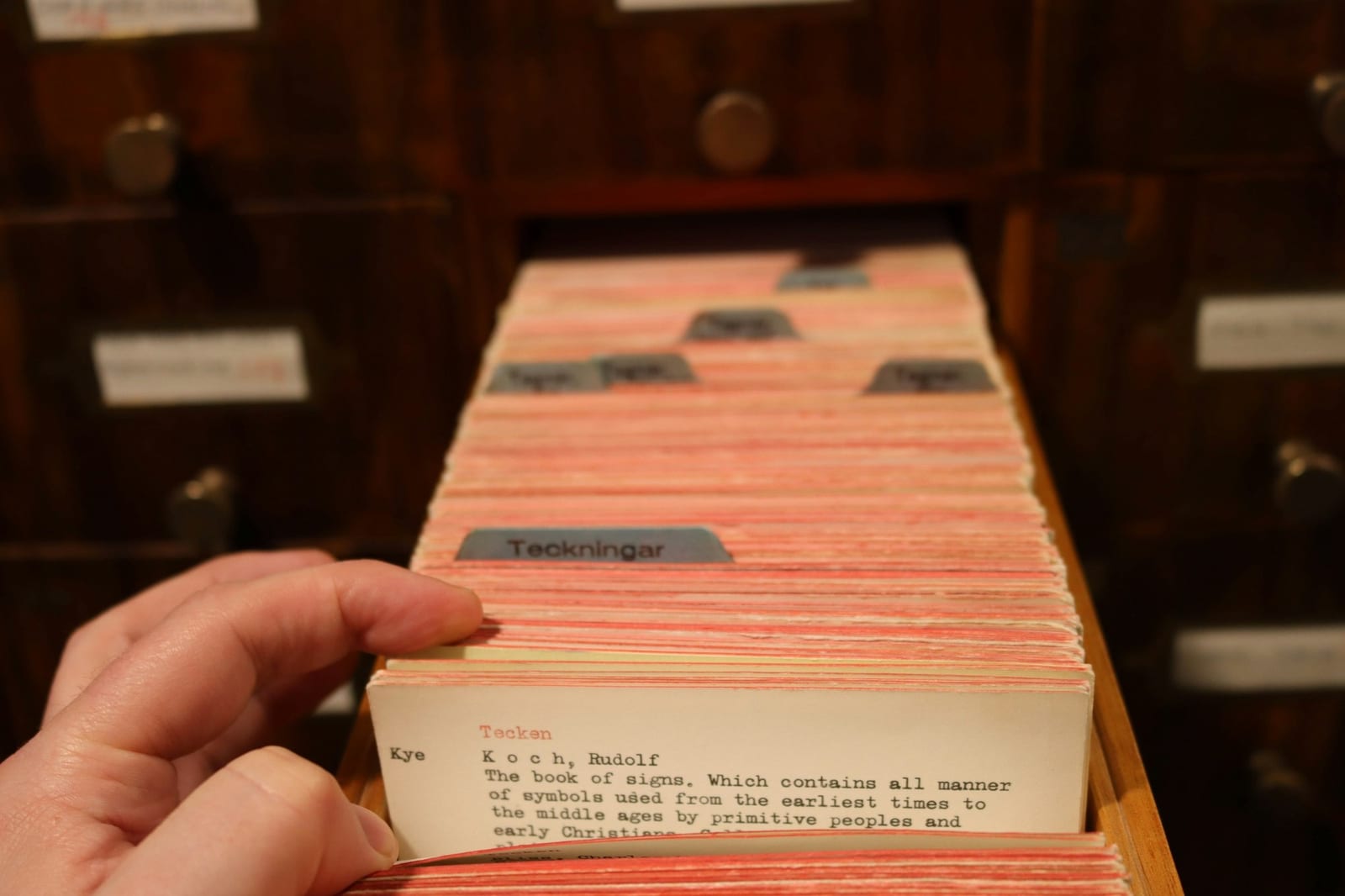 Una mano hojea las fichas de un antiguo fichero de biblioteca: buscar en el registro qué fue de una idea.